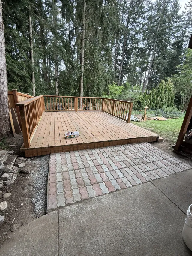 Wood deck with vertical railings beside a paved patio